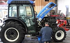 Man working on a New Holland tractor within the SS Equipment service department.